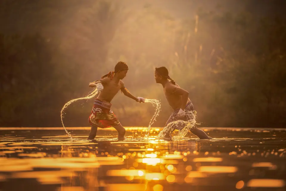 Dois lutadores treinando na água ao pôr do sol